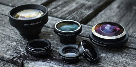 Five different camera lenses labeled with their types are arranged on a weathered wooden surface.