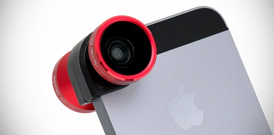 A red clip-on camera lens is attached to the corner of a silver smartphone with an Apple logo.