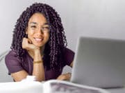 A woman with curly hair sitting at a desk with a laptop.