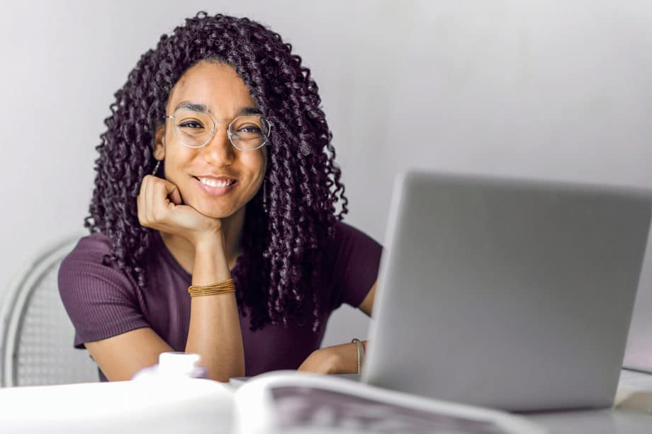 A woman with curly hair sitting at a desk with a laptop.