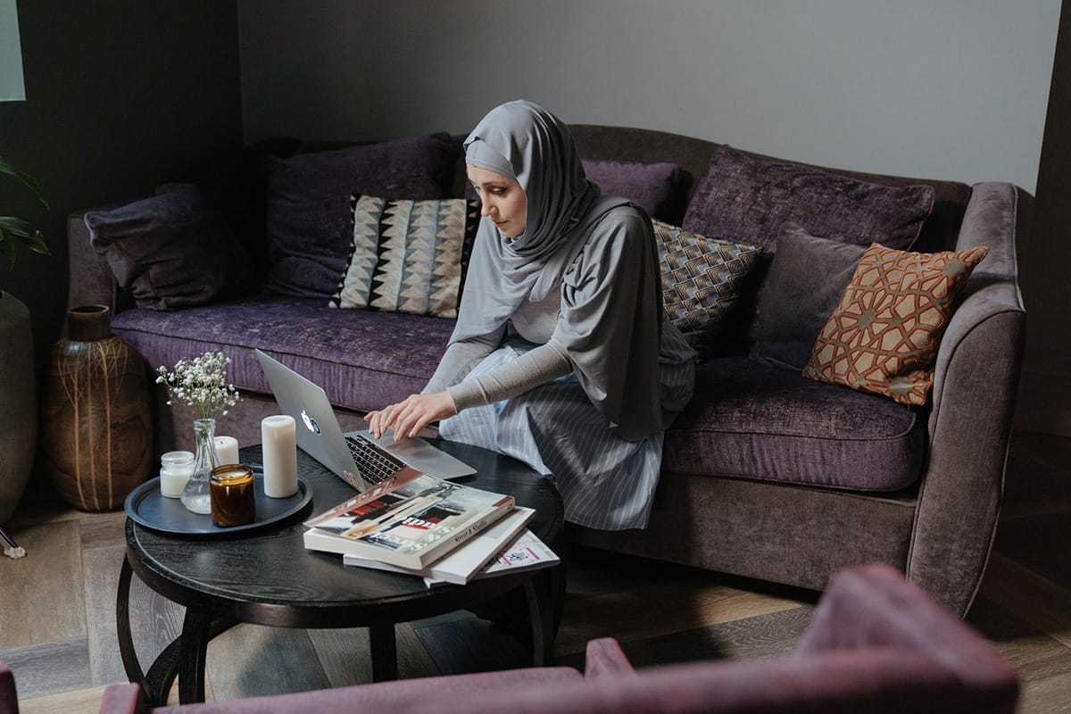 A muslim woman using a laptop in her living room.