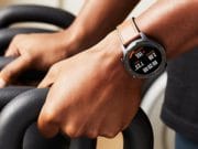 Close-up of a person gripping a kettlebell handle, wearing a smartwatch displaying heart rate and workout stats.