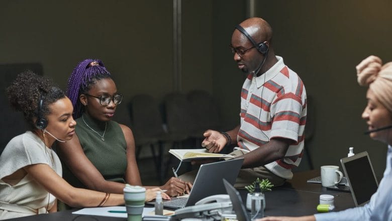 A group of people working together in a conference room of a call center.