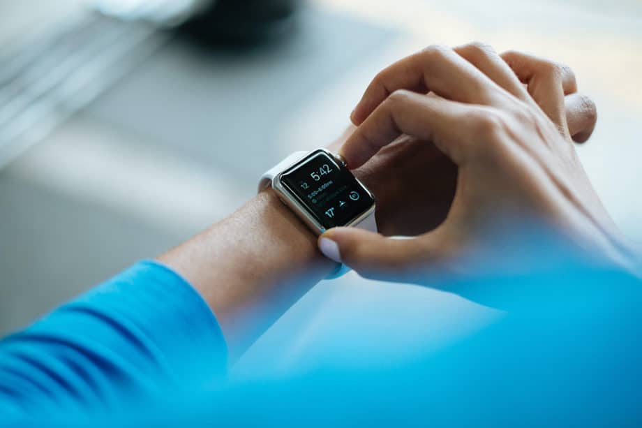A person interacts with a smartwatch displaying the time, date, and notifications.