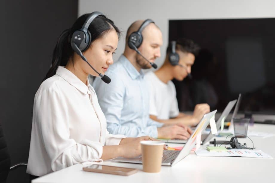 A group of people using headsets in a call center.