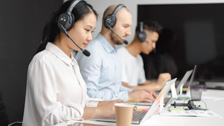 A group of people using headsets in a call center.