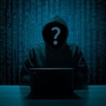 A hooded figure at a laptop with a question mark over their face, set against a backdrop of digital numbers.