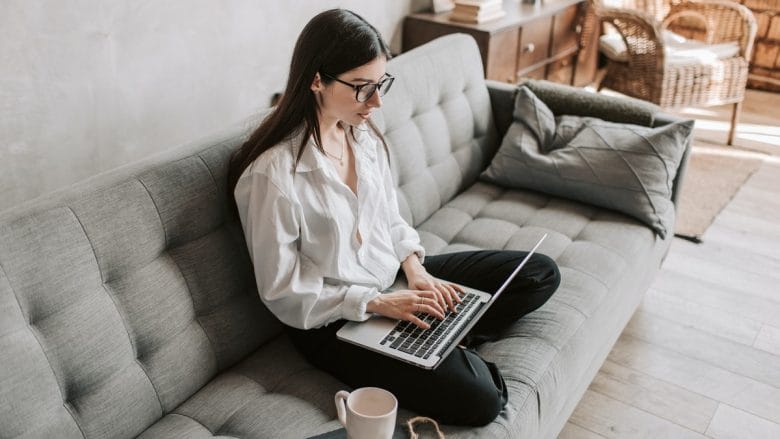 A woman sitting on a couch with a laptop.