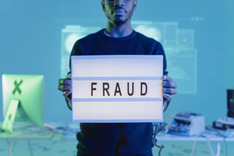 A man holding up a sign that says fraud.