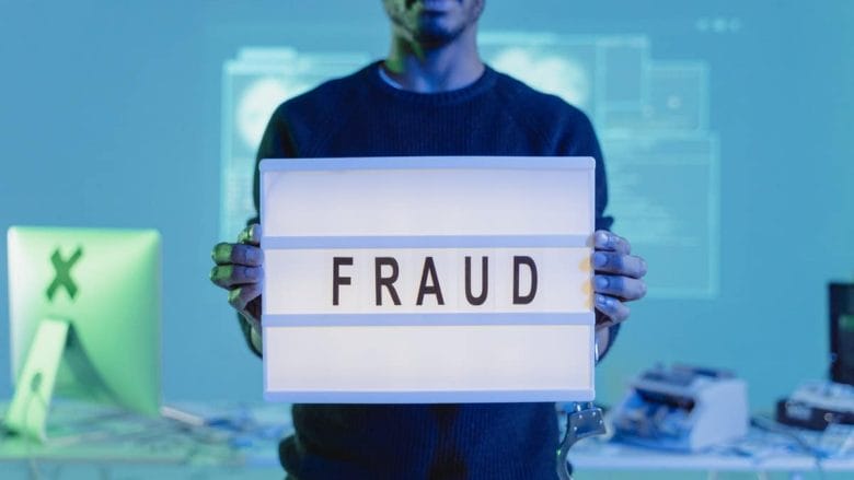 A man holding up a sign that says fraud.