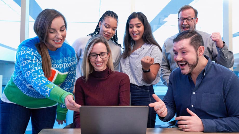 A group of people standing around a laptop.