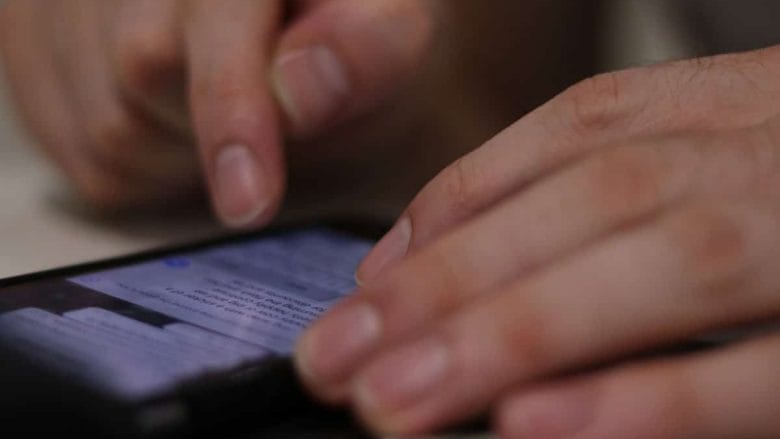A person uses their fingers to scroll through messages on a smartphone screen.