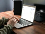 A man using a laptop on a desk and working on a wordpress dashboard.