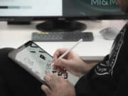 A man is using an apple pencil to draw on an ipad.