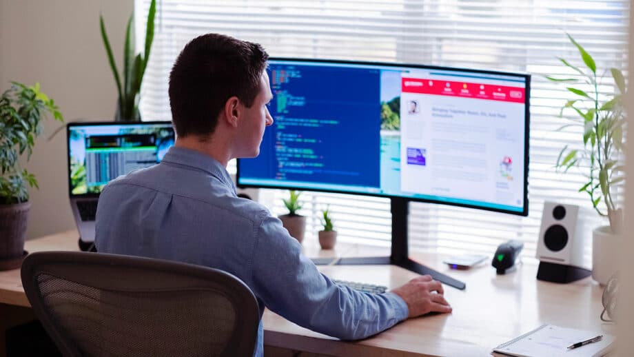 A developer sitting at a desk with two monitors in his office.