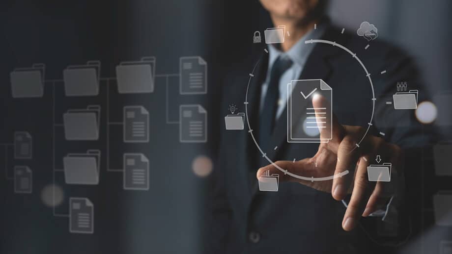 A man in a suit is pointing at a document icon on a screen and planning for an automated marketing strategy.