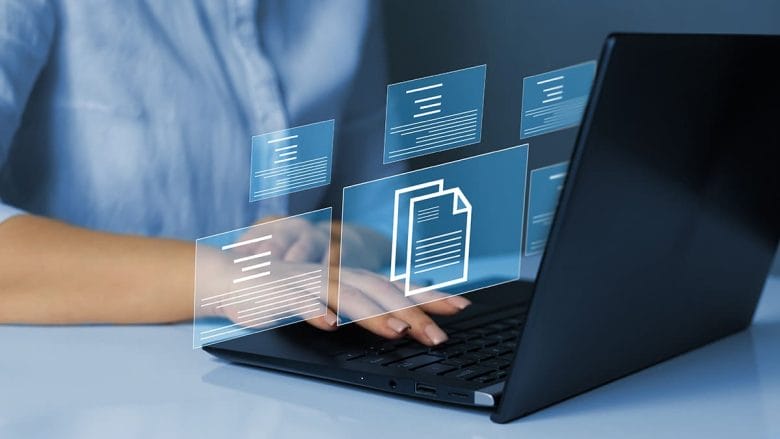 Person typing on a laptop with floating digital document icons displayed above the keyboard.