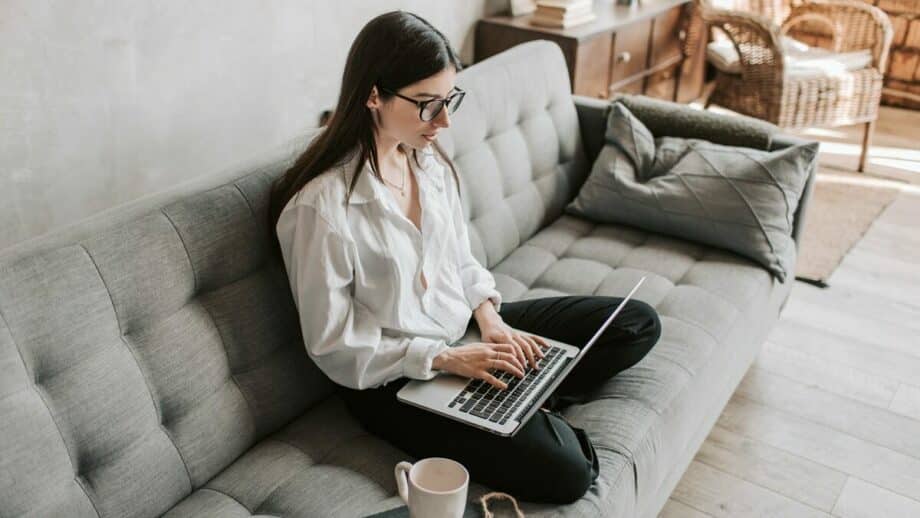 A woman sitting on a couch with a laptop.