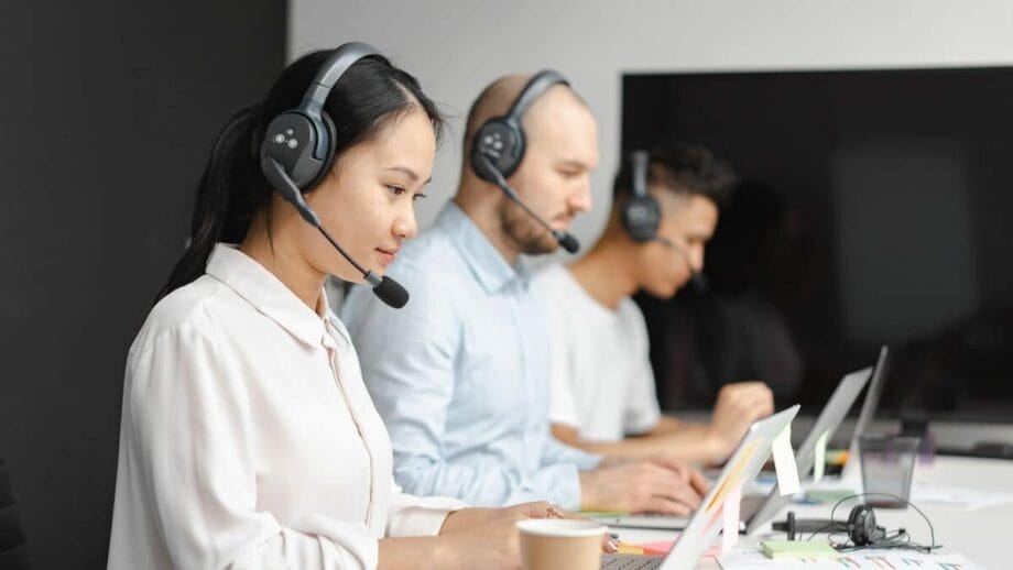 A group of people using headsets in a call center.