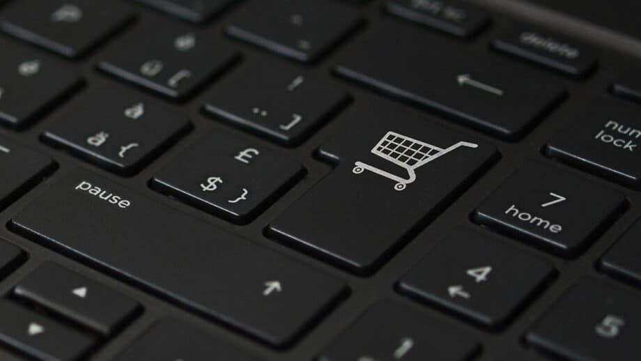 Close-up of a black computer keyboard with a focus on a key featuring a shopping cart icon, symbolizing online shopping, surrounded by other keys including pound and home keys.