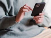 A woman holding a phone while sitting on a couch.