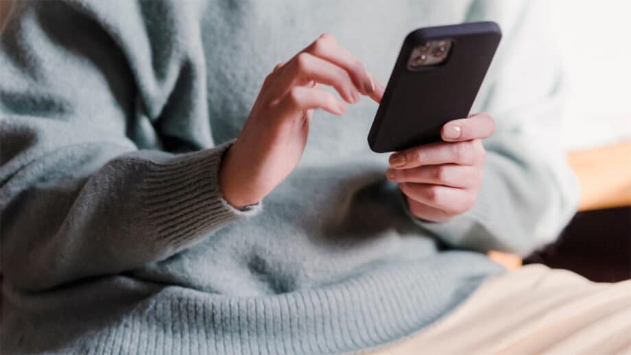 A woman holding a phone while sitting on a couch.