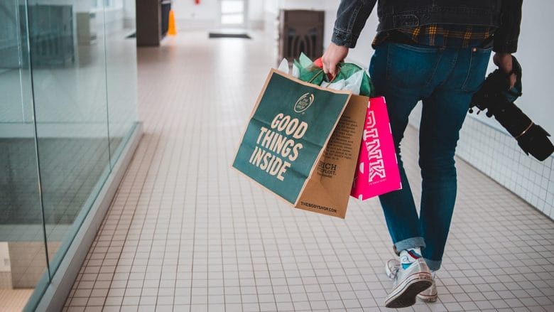 A person walking down a hallway with shopping bags.