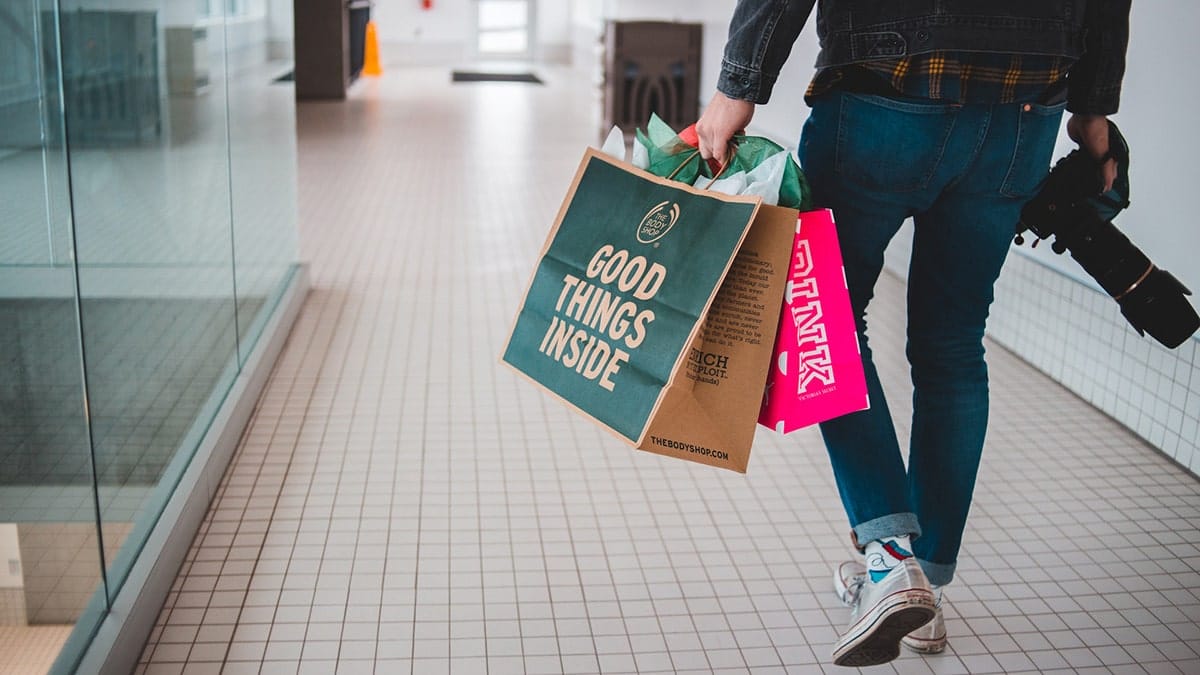 A person walking down a hallway with shopping bags.