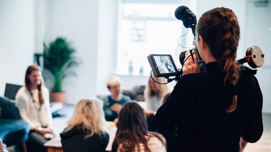 A woman holding a video camera in front of a group of people.