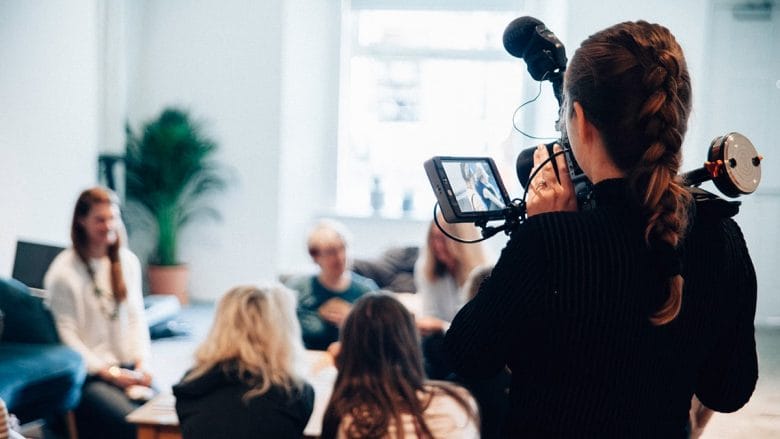 A woman holding a video camera in front of a group of people.