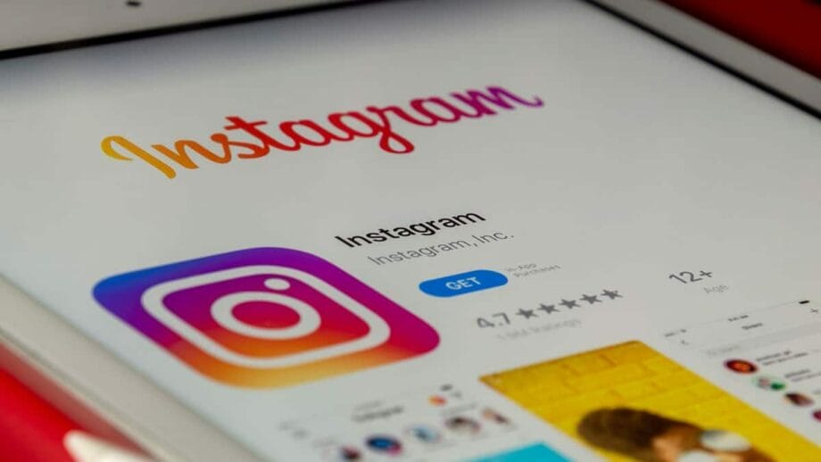 A tablet screen displays the Instagram app page in the app store, showing the app’s logo, rating, and install button.
