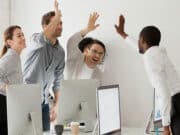 A group of people raising their hands in the air in an office.