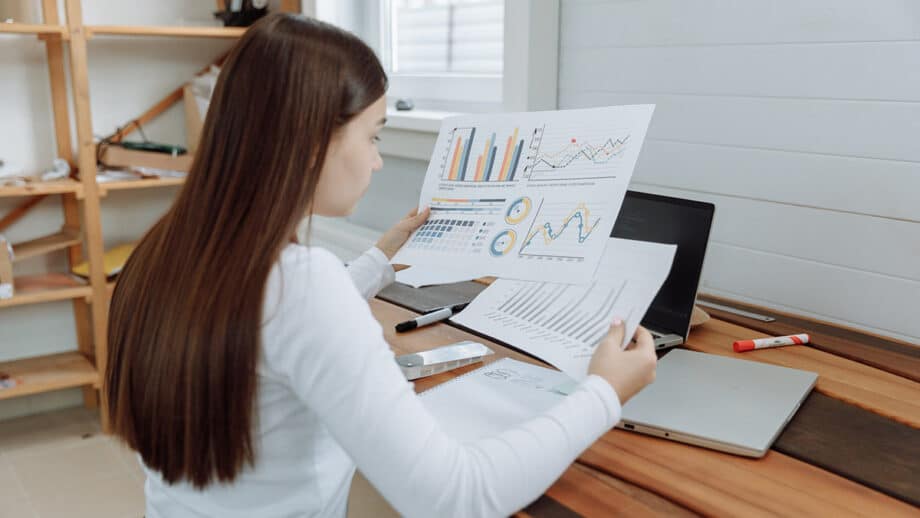 A woman is looking at graphs on a laptop.