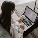 A woman working on her laptop in a living room.