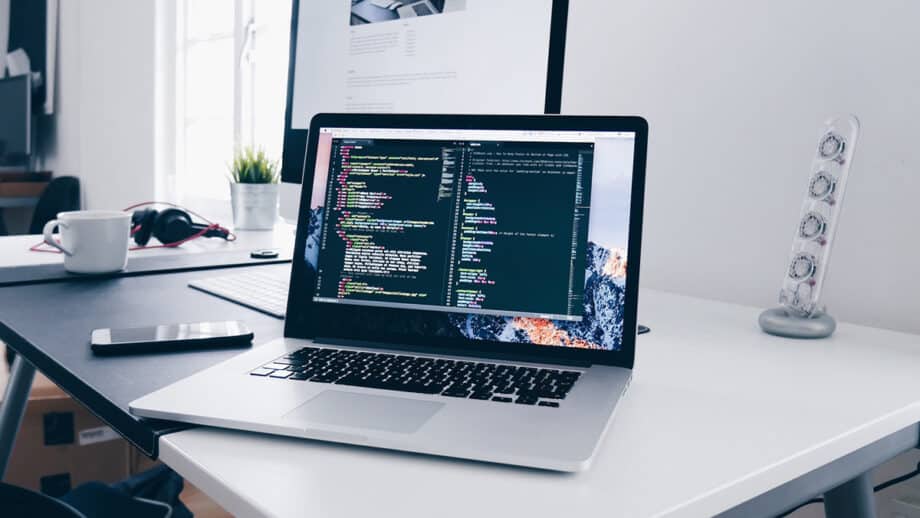 A laptop is sitting on a desk with code on it.