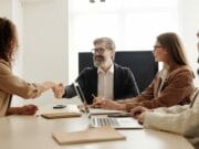 A group of business people shaking hands at a meeting.