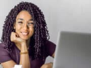A woman with curly hair sitting at a desk with a laptop.