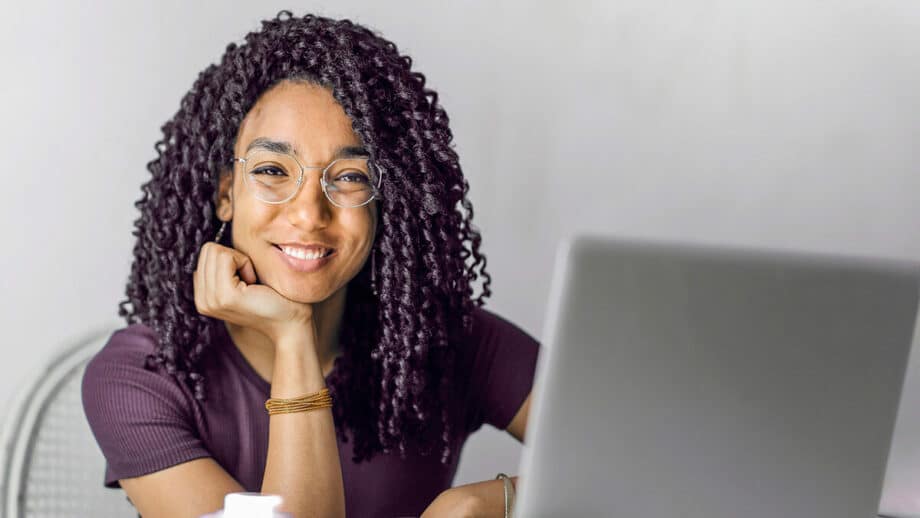 A woman with curly hair sitting at a desk with a laptop.