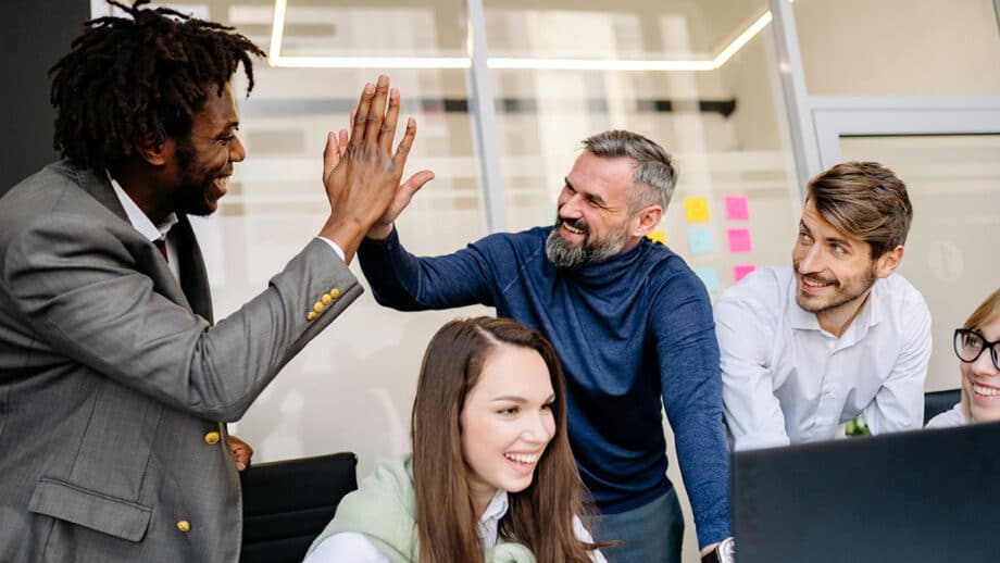 A group of people giving each other high fives in an office.