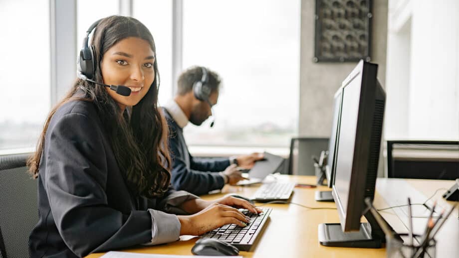 One woman and one man working at a computer in a call center.