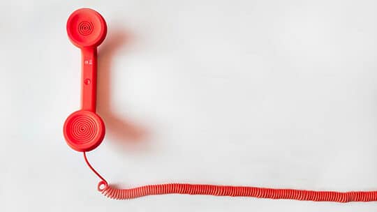 A red telephone on a white background.