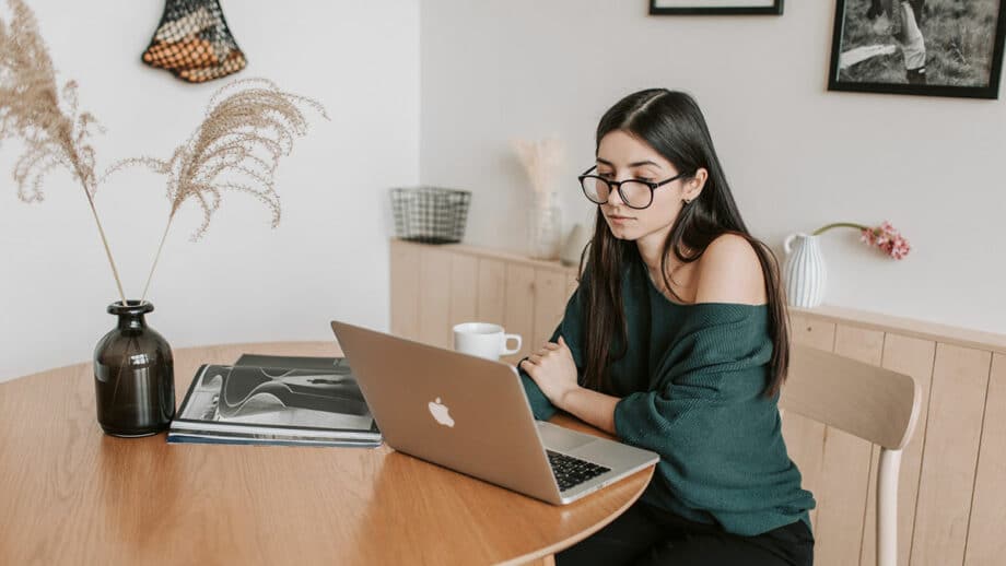 A woman sitting at a table with a laptop thinking about the lead generation for her startup.