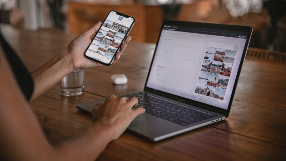 A woman is using a laptop and a mobile phone to develop a website.