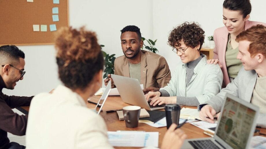 A group of people sitting around a table with laptops.