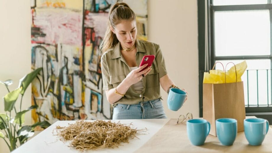 A woman looking at her phone while sitting on a table.