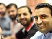 A group of men wearing headsets in a call center.