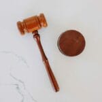 A wooden judges gavel and sound block on a white marble surface.