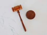 A wooden judges gavel and sound block on a white marble surface.