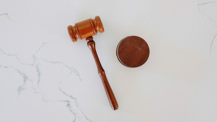 A wooden judges gavel and sound block on a white marble surface.