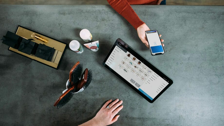 A group of people sitting at a table with a laptop, and a smartphone.